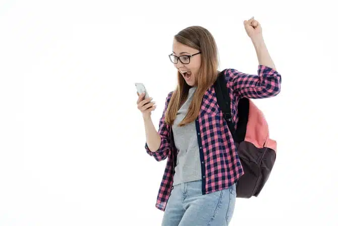 Student looking at her phone and grinning while shaking her fist in the air